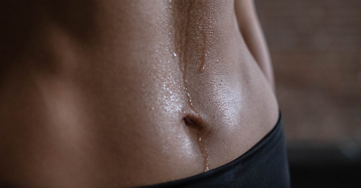 A close-up of a fit woman's toned abdomen with sweat, emphasizing fitness and strength.