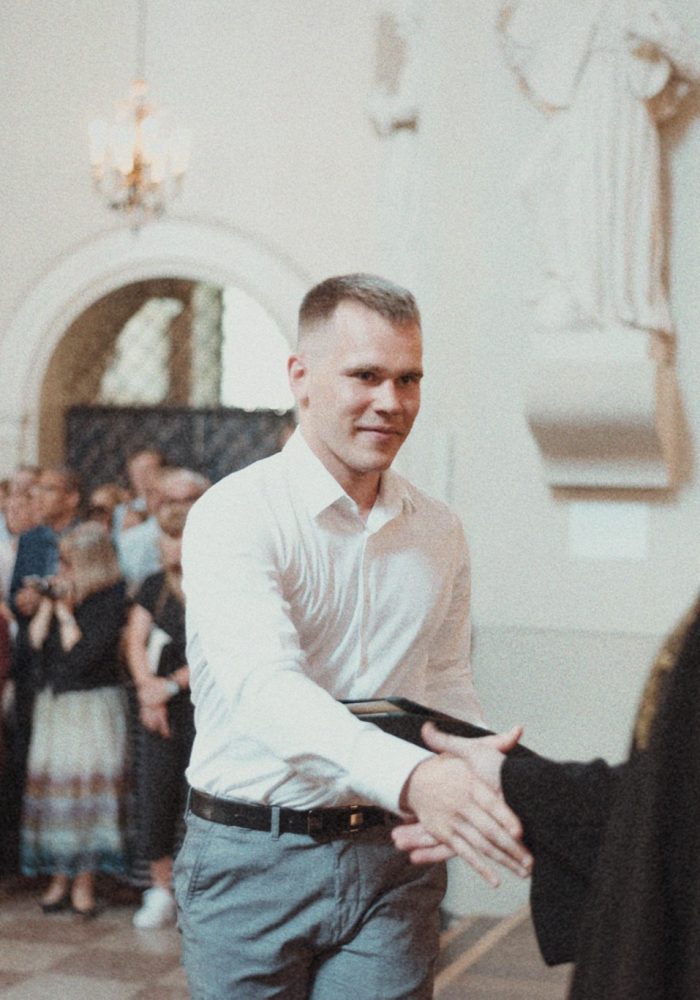 Dr. Žygimantas Mačys proudly holding his diploma after graduating from medical school